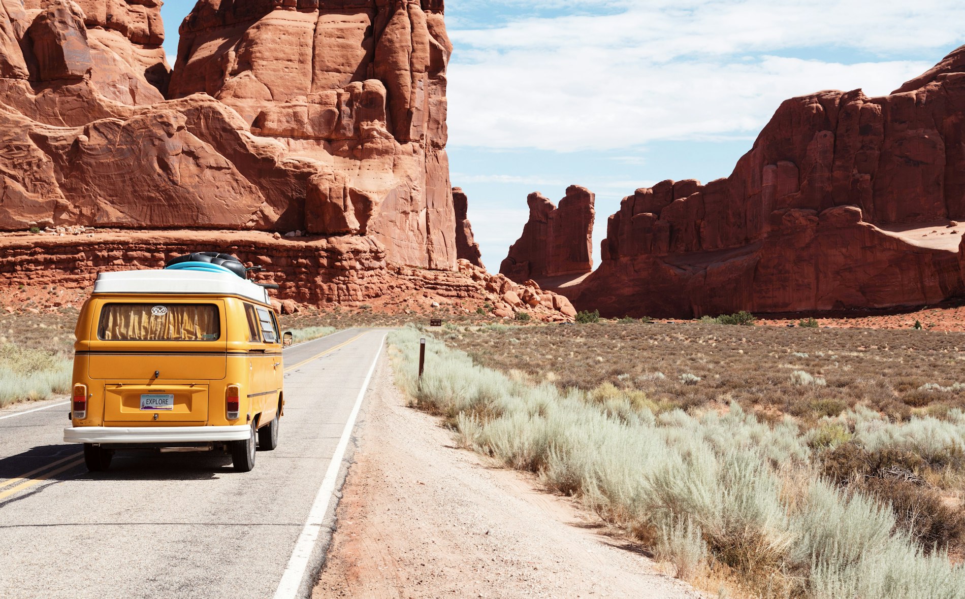 An open road winding toward distant mountains at golden hour