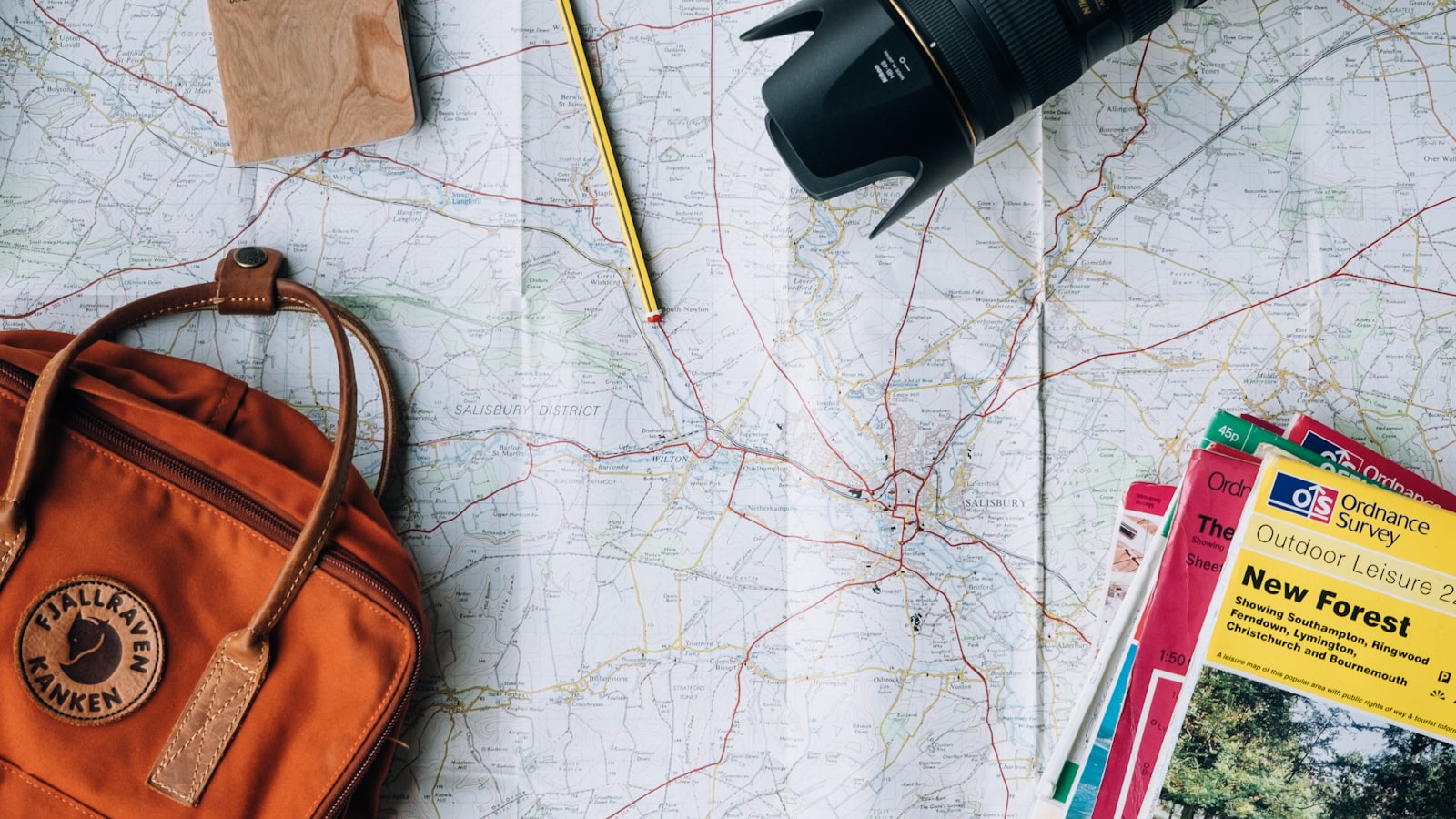 A traveller's open notebook, map, and coffee cup on a wooden table while planning a journey